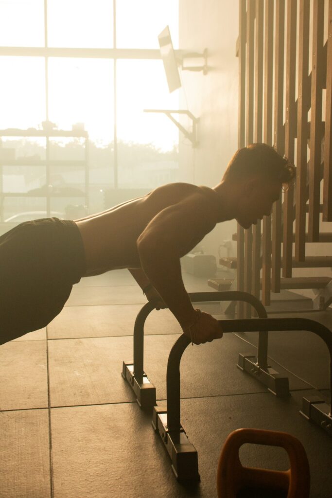 Person performing controlled push-ups on a patio beside a pull-up bar and exercise mat.