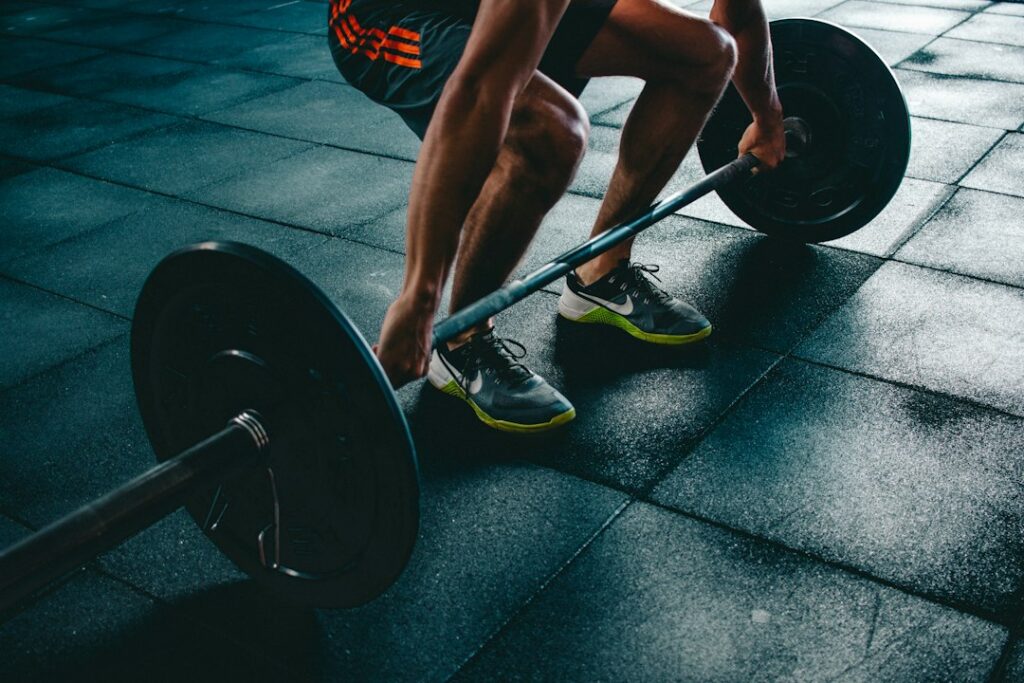Beginner lifting dumbbells in a bright gym while following a written full-body workout plan