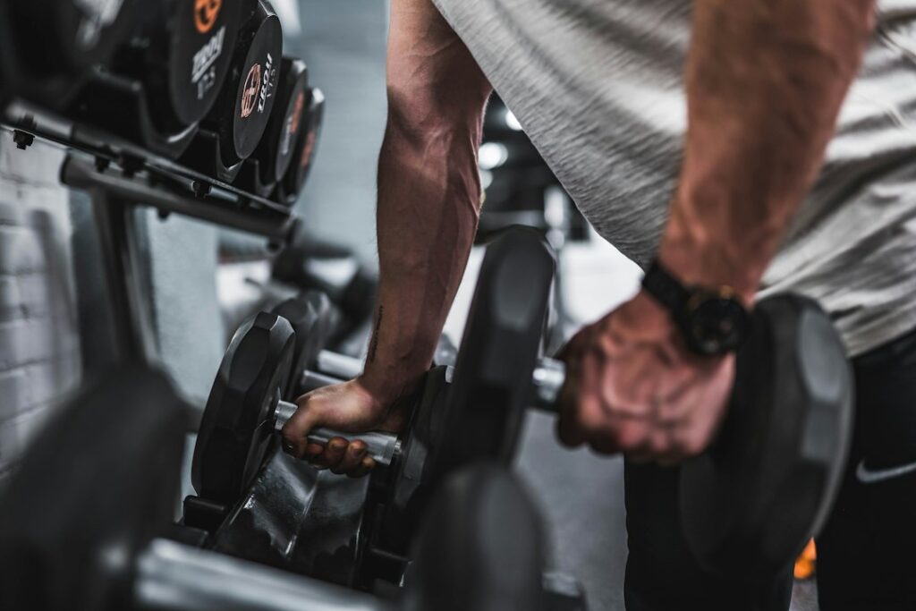 Adult lifter performing controlled dumbbell exercises in a bright home workout space.