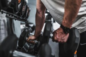Adult lifter performing controlled dumbbell exercises in a bright home workout space.